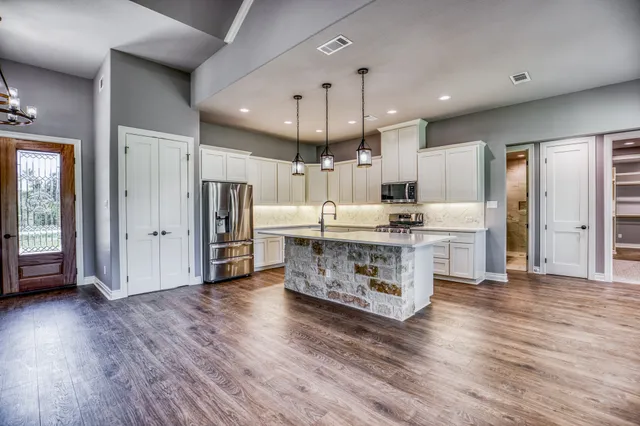 a kitchen with stainless steel appliances a refrigerator and wooden floor