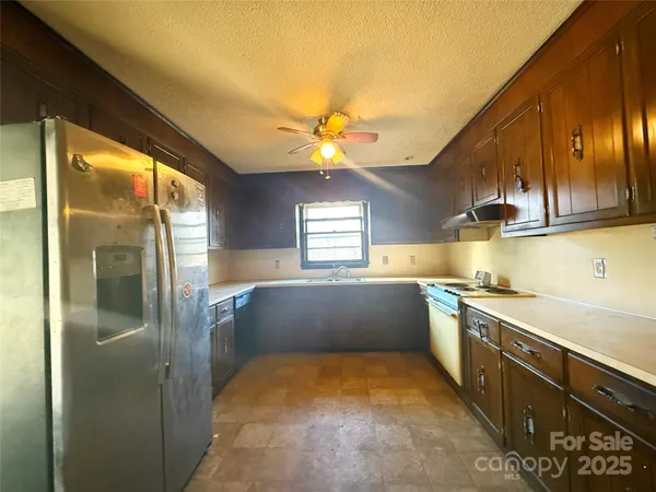 a kitchen with stainless steel appliances granite countertop a sink refrigerator and cabinets