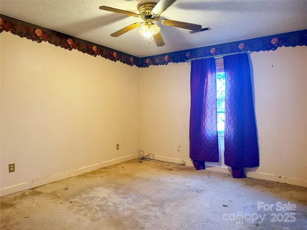 an empty room with a window and ceiling fan