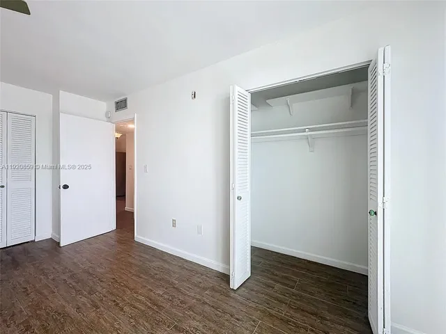 a view of an empty room with wooden floor & closet