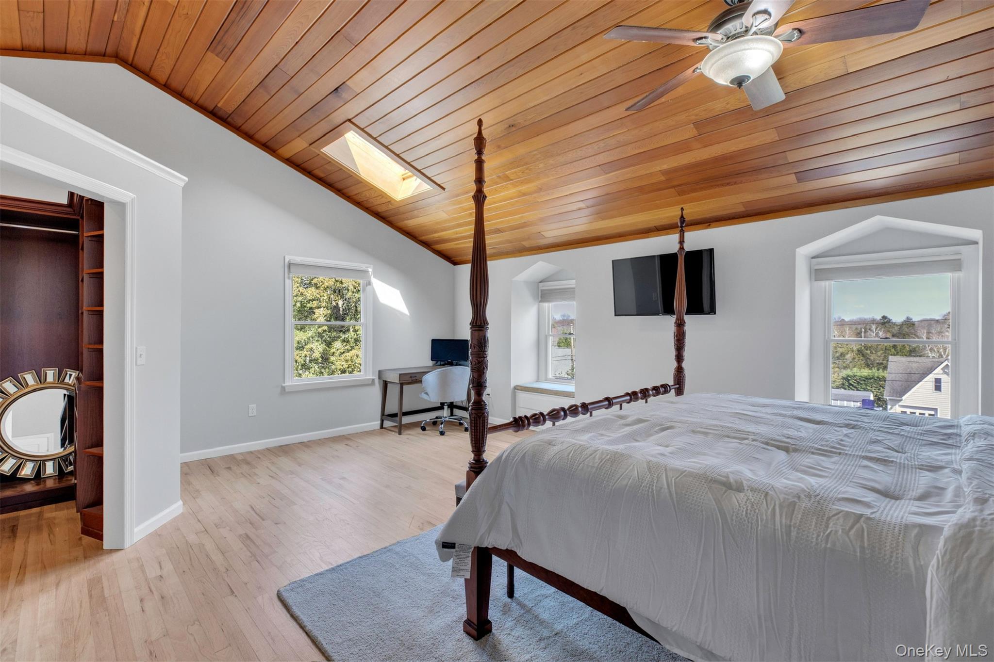 345 Colonial Road Southold, NY 11971 - Photo 22 of 43 a spacious bedroom with a bed a table and painting on the wall