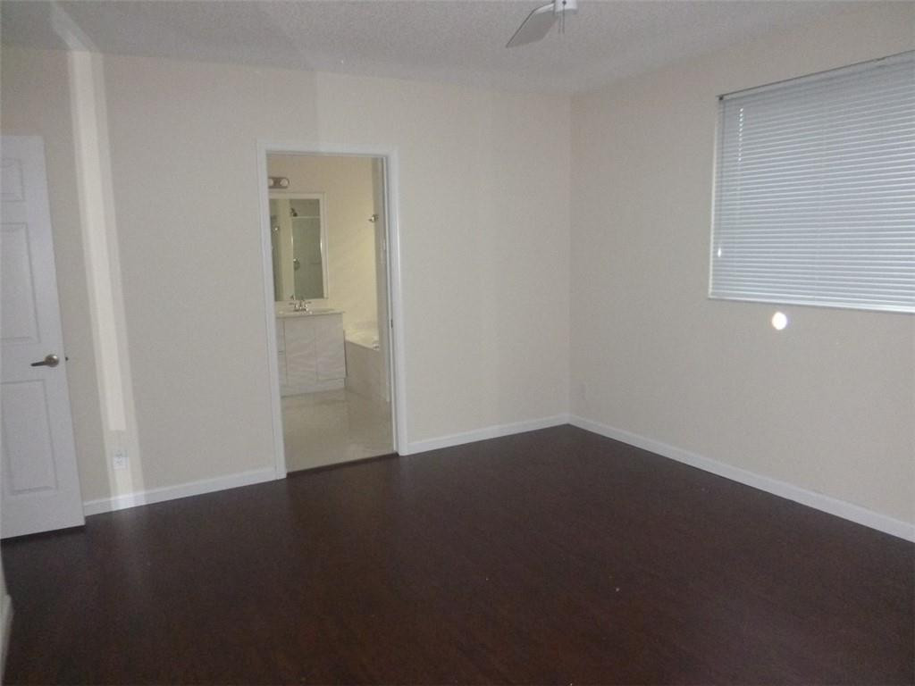 745 Falling Water Road Weston, FL 33326 - Photo 23 of 34 an empty room with wooden floor and windows with curtains