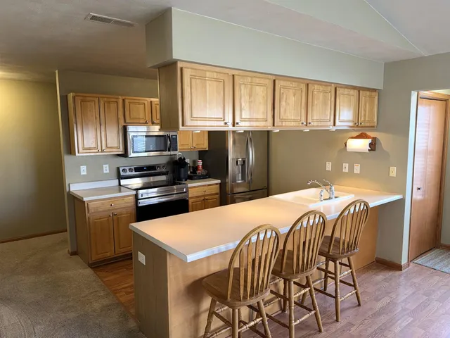 a kitchen with a refrigerator a stove top oven a sink dishwasher and wooden cabinets
