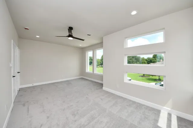 an empty room with windows and a ceiling fan