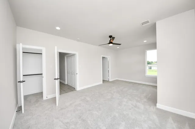 an empty room with windows and ceiling fan