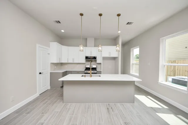 a large white kitchen with a large window a sink and stainless steel appliances