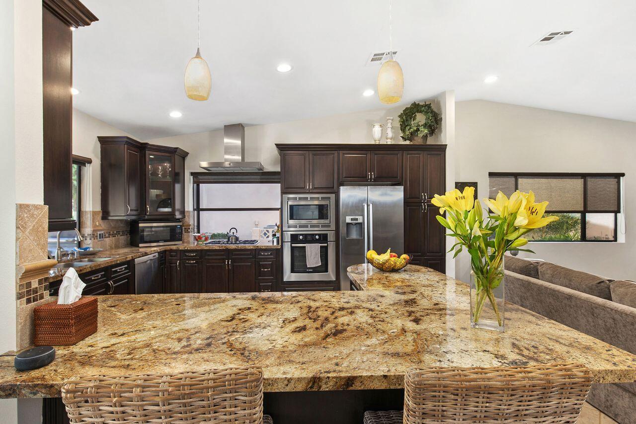 45250 Vista Santa Rosa Indian Wells, CA 92210 - Photo 18 of 28 a kitchen with kitchen island granite countertop wooden cabinets and a granite counter tops
