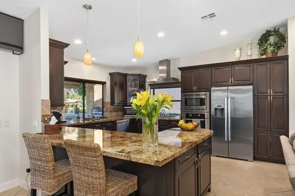 a kitchen with stainless steel appliances granite countertop a refrigerator a sink dishwasher and microwave