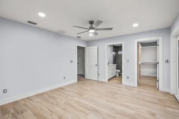 a view of an empty room with wooden floor and window
