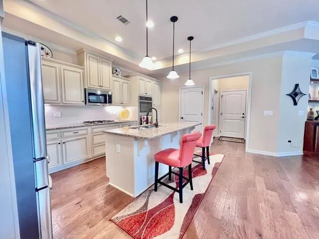 a kitchen with stainless steel appliances kitchen island granite countertop a stove a sink a refrigerator and chairs