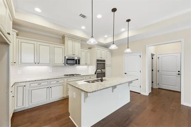 a kitchen with kitchen island granite countertop a stove a sink a center island and wooden floor