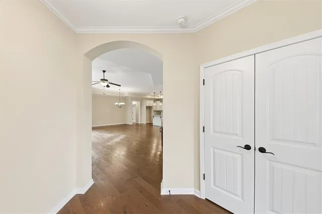 a view of a hallway with wooden floor closet and windows