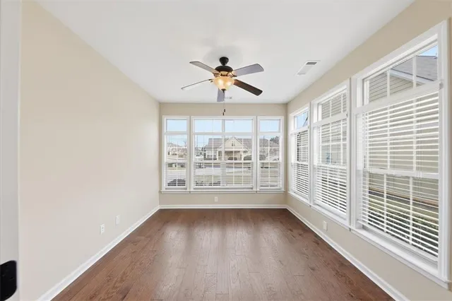 a view of empty room with wooden floor and ceiling fan