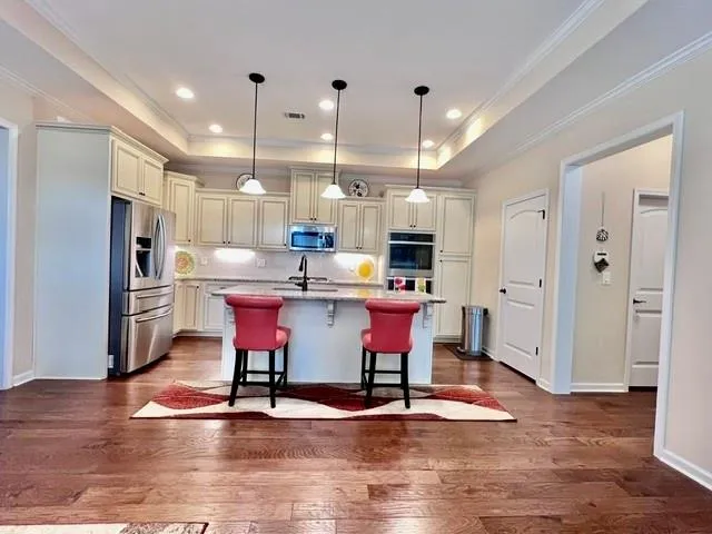 a kitchen with stainless steel appliances kitchen island granite countertop a table chairs sink refrigerator and cabinets