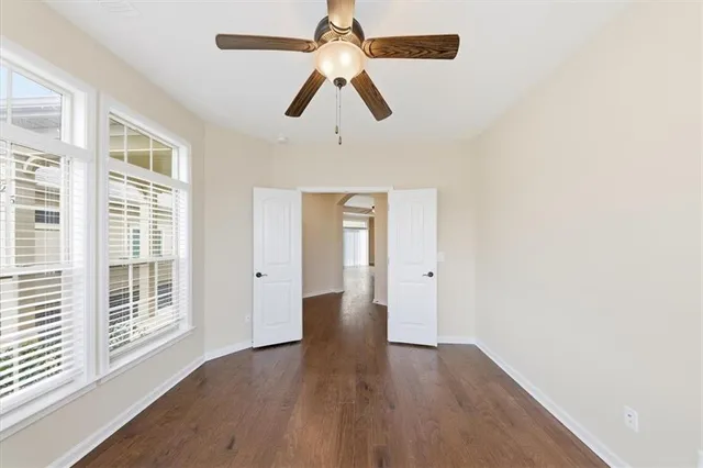 a view of empty room with wooden floor and fan