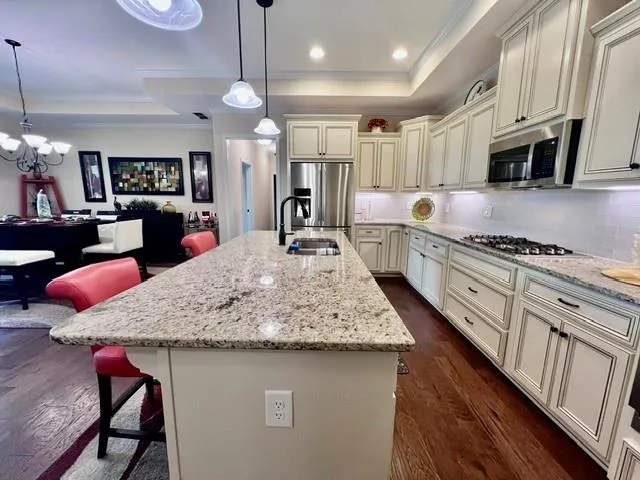 a kitchen with stainless steel appliances kitchen island granite countertop a table chairs in it and wooden floors