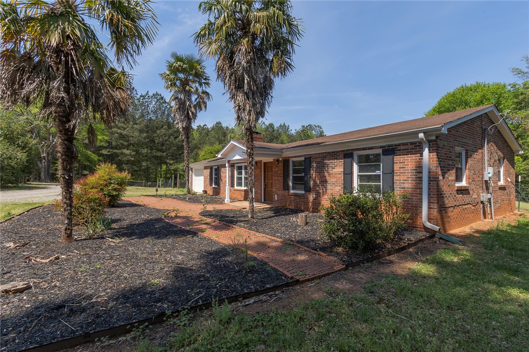 820 Travis Road Anderson, SC 29626 - Photo 9 of 46 This classic brick residence features an inviting facade with lush landscaping and mature palm trees.