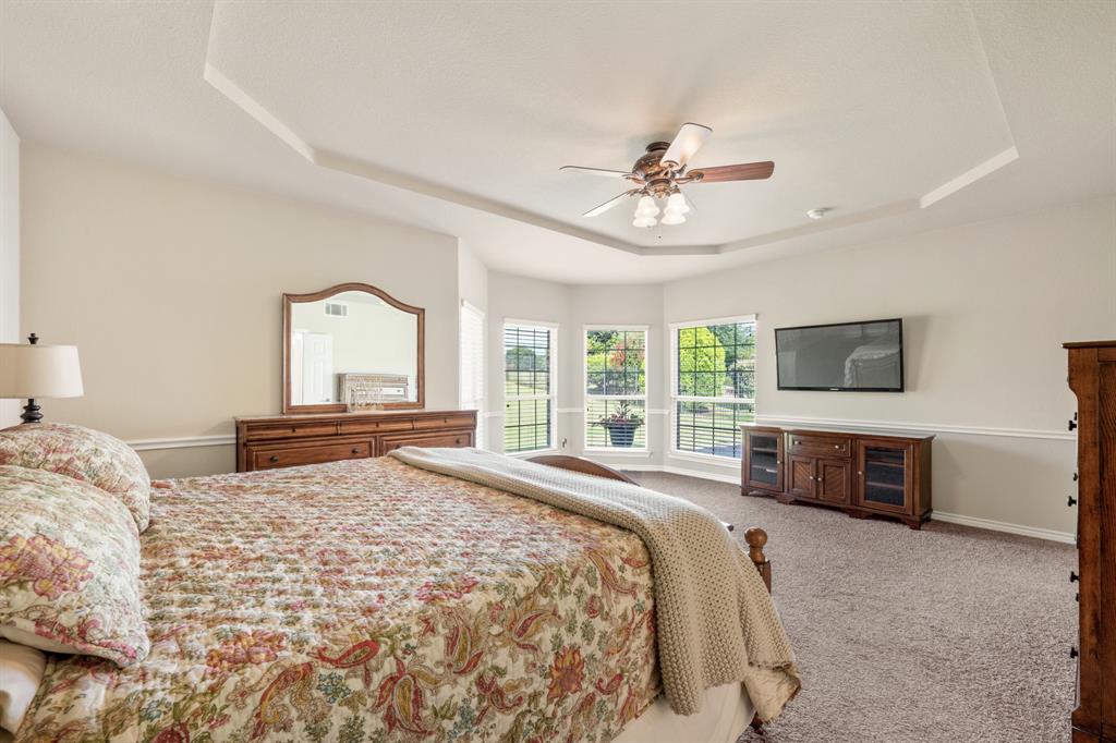 10601 Huffines Drive Rowlett, TX 75089 - Photo 14 of 29 a bedroom with a large bed a flat tv screen and a dresser