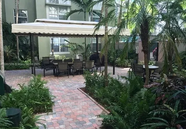 a view of a patio with table and chairs potted plants and large tree