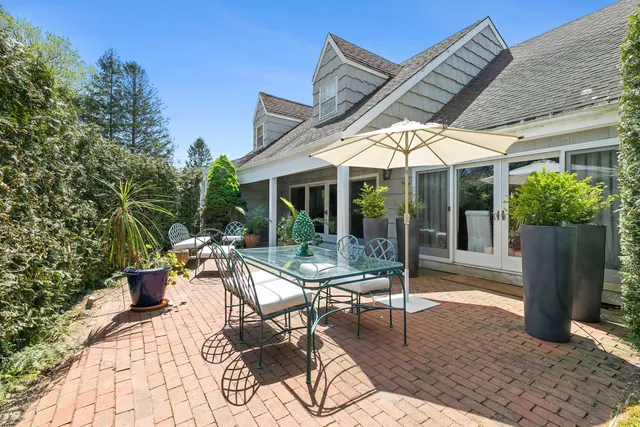 a view of a patio with table and chairs potted plants and floor to ceiling window
