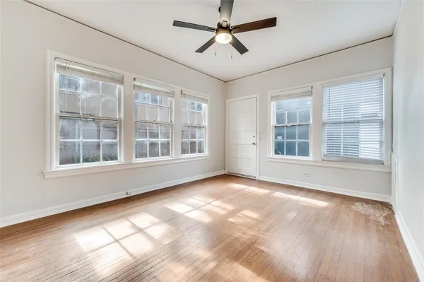 a view of an empty room with a window and wooden floor