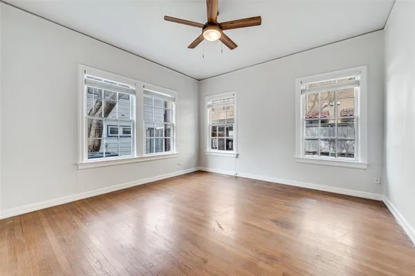 a view of an empty room with window and wooden floor