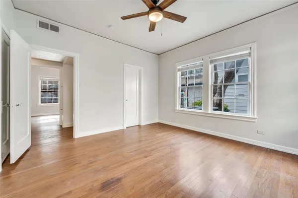 a view of an empty room with window and wooden floor