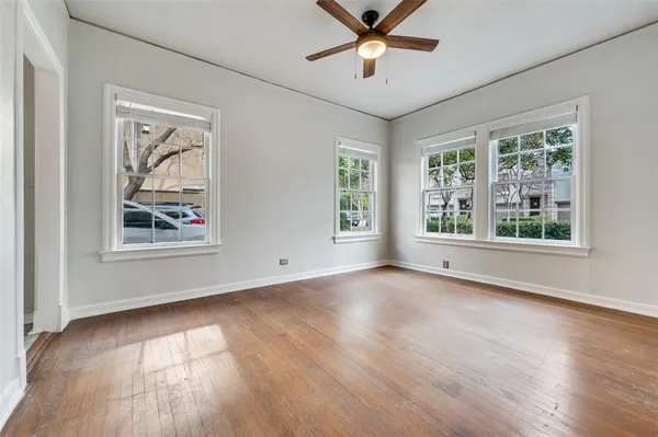 a view of an empty room with a window and wooden floor