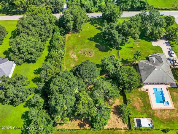 an aerial view of residential houses with outdoor space and trees all around