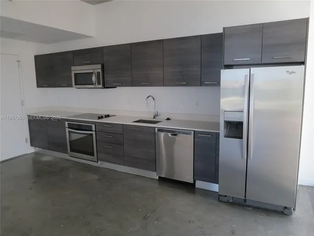 a kitchen with stainless steel appliances a refrigerator a sink a stove and cabinets