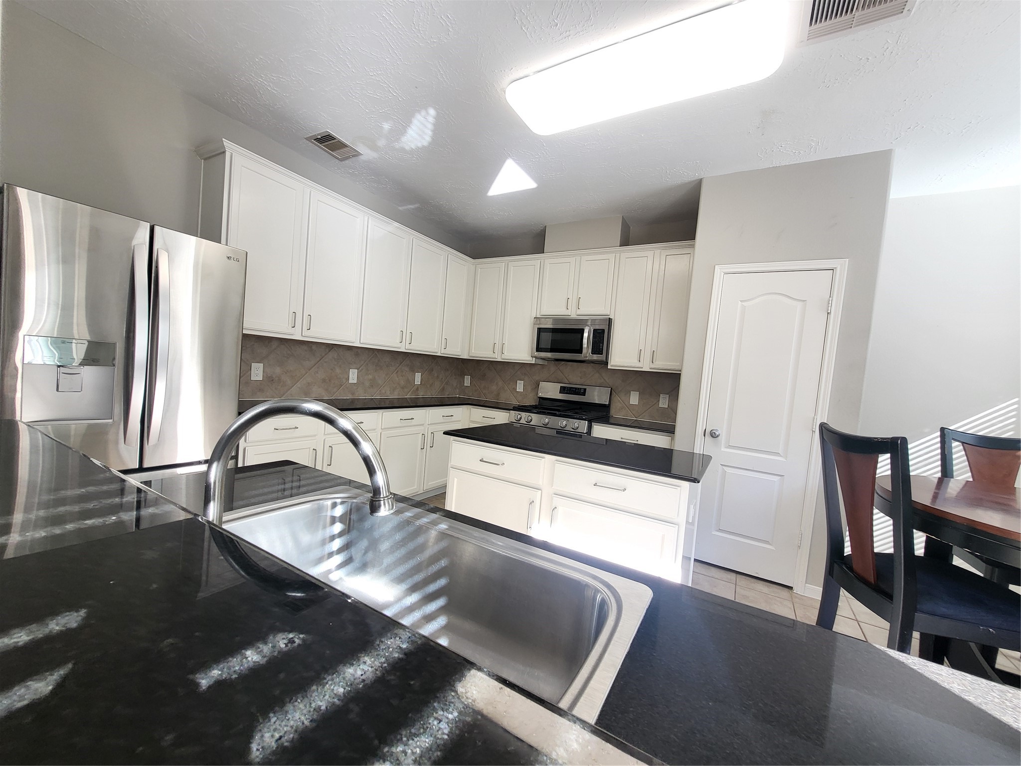 7415 Hollister Ridge Houston, TX 77040 - Photo 11 of 36 a kitchen with stainless steel appliances granite countertop a refrigerator a stove a sink dishwasher a dining table and chairs with wooden floor