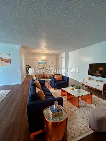 a living room with furniture a flat screen tv and kitchen view