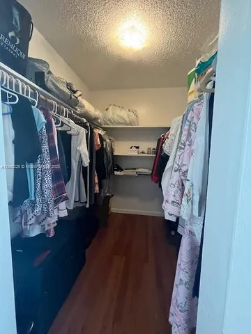 a view of walk in closet with clothes and shoes