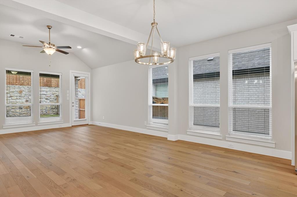 4123 Windy Point Court Oak Point, TX 75068 - Photo 12 of 29 Spacious room featuring vaulted ceilings, light wood-finish flooring, multiple windows, a ceiling fan, and a contemporary chandelier