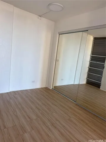 a view of an empty room with wooden floor and stairs