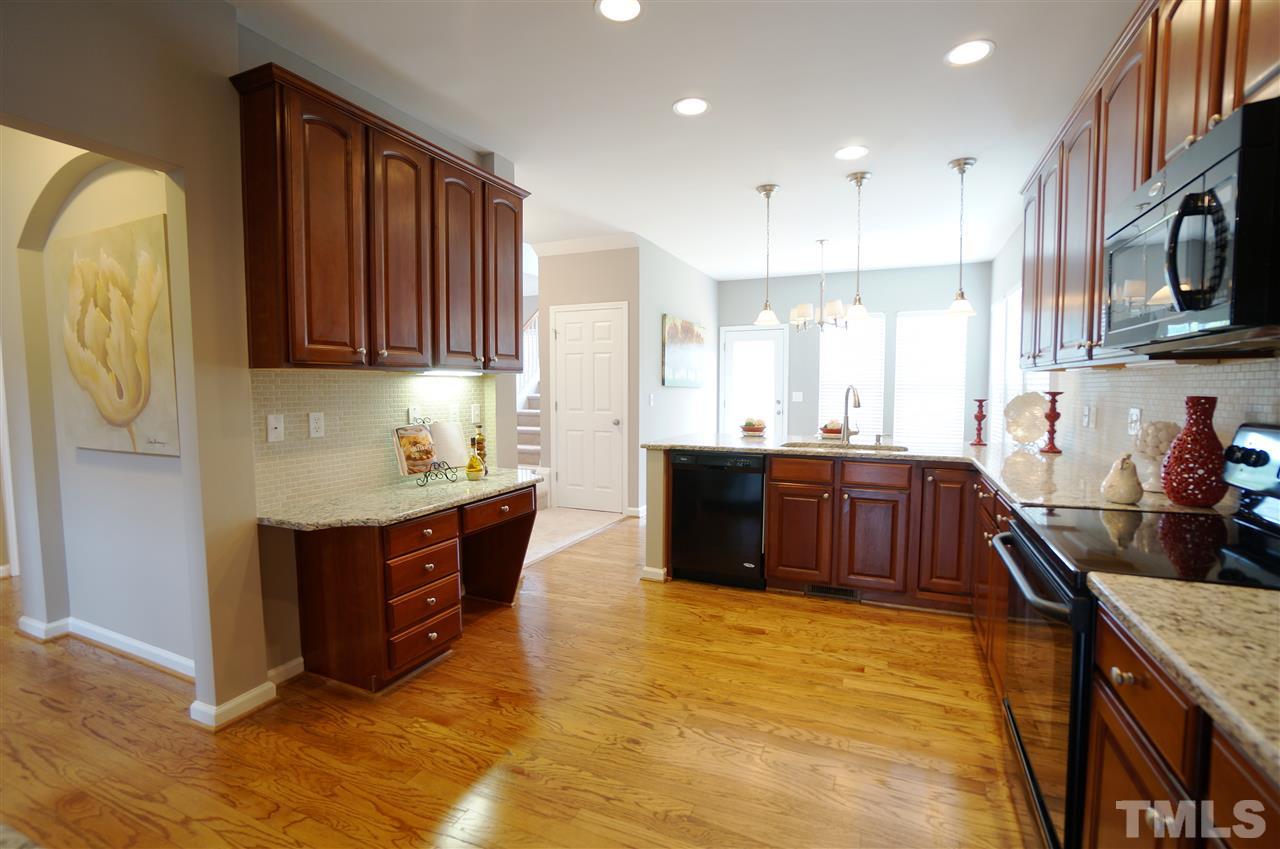 7730 San Gabriel Street Raleigh, NC 27613 - Photo 3 of 25 Spacious kitchen has an open layout, granite counter tops, tile back splash, under cabinet lighting, charm, style & sophistication.