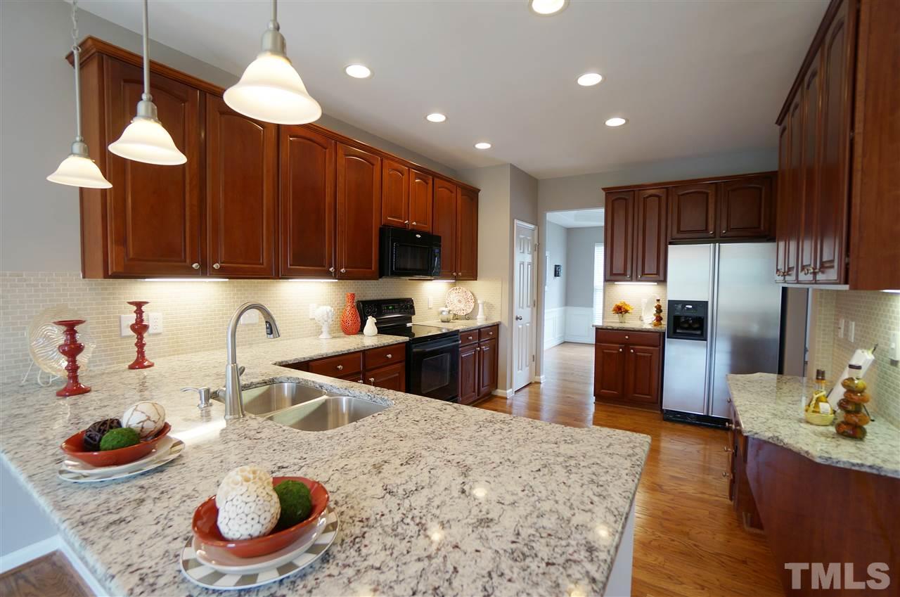 7730 San Gabriel Street Raleigh, NC 27613 - Photo 4 of 25 Spacious kitchen has an open layout, granite counter tops, tile back splash, under cabinet lighting, charm, style & sophistication.