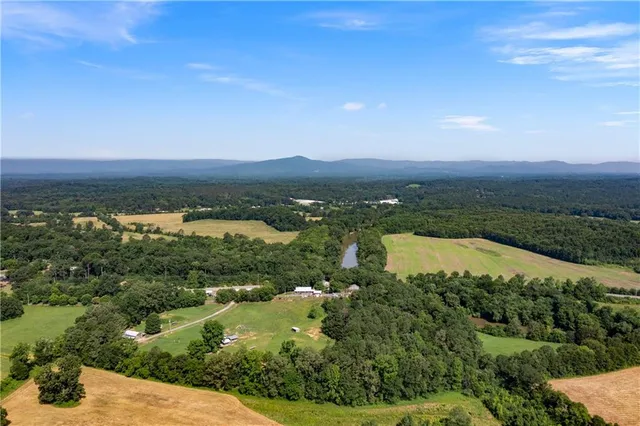 an aerial view of a residential houses with outdoor space and trees all around