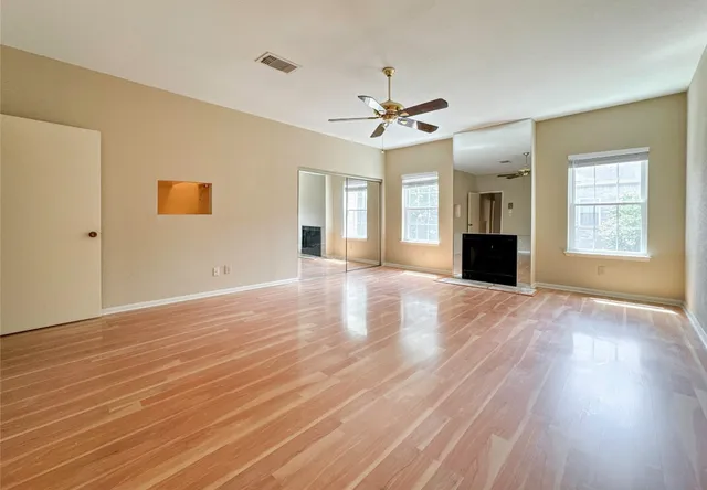 a view of an empty room with window and wooden floor
