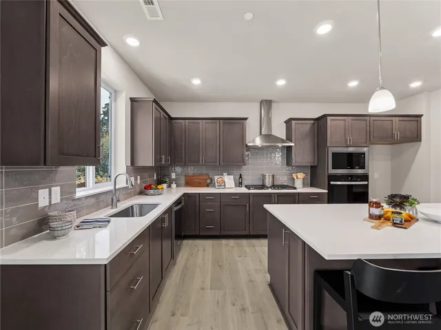 a kitchen with kitchen island granite countertop a sink counter space cabinets and stainless steel appliances