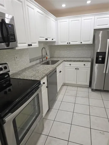 a kitchen with granite countertop a stove a sink and a refrigerator