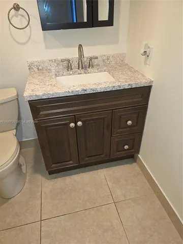 a bathroom with a granite countertop sink a toilet and mirror