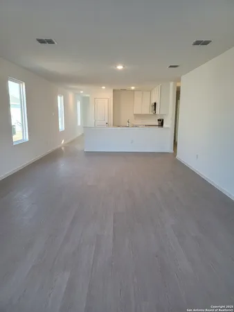 a view of an empty room and a kitchen