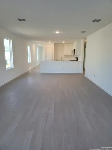a view of an empty room and a kitchen