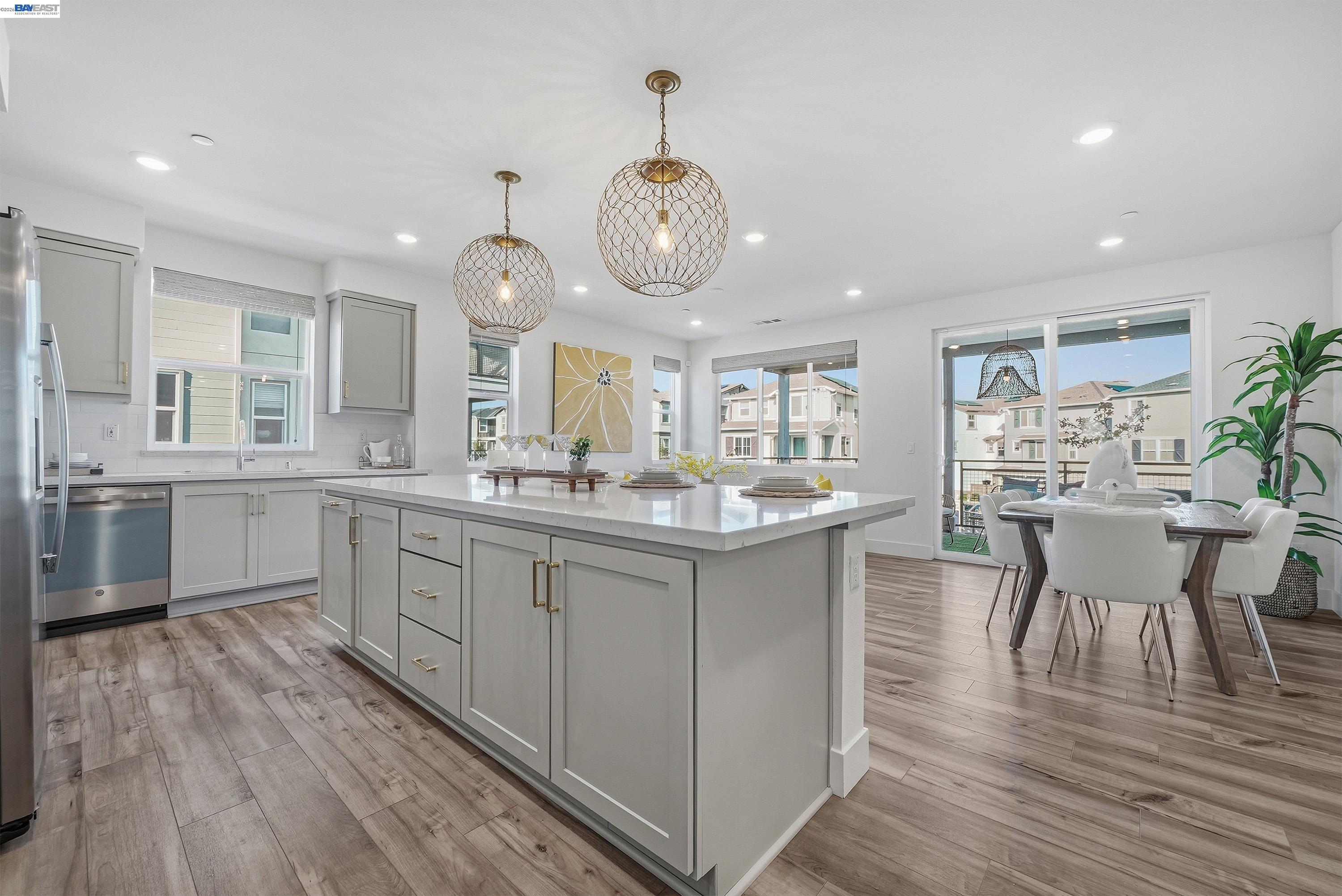 9620 Seawind Way Newark, CA 94560 - Photo 47 of 55 a kitchen with a dining table chairs wooden floor and white cabinets