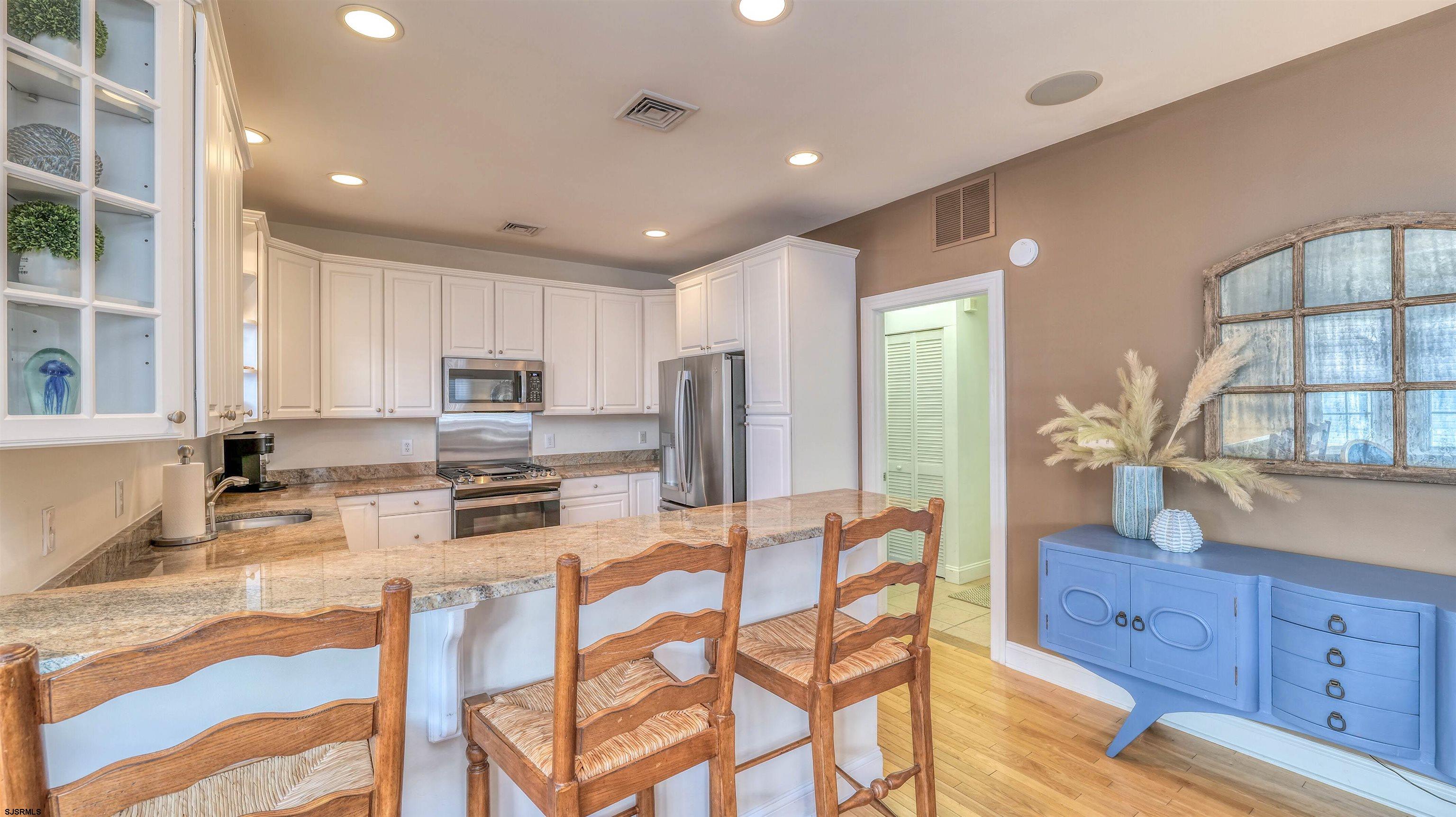 119 North Belmont Avenue, Unit AUGUST LABOR DAY Margate City, NJ 08402 - Photo 12 of 35 a kitchen with stainless steel appliances granite countertop a stove a sink dishwasher a dining table and chairs with wooden floor
