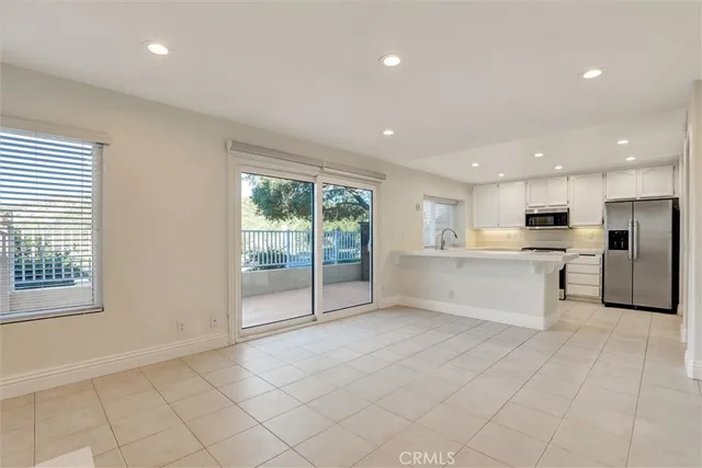 a large white kitchen with a large window and stainless steel appliances