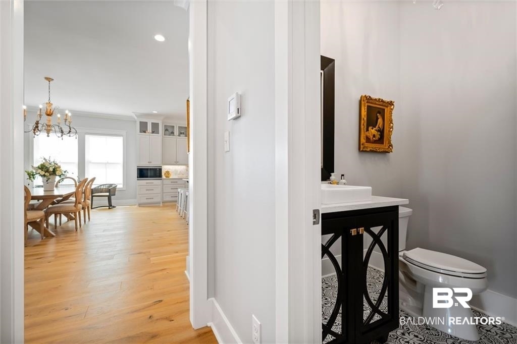 707 Cardamel Court Fairhope, AL 36532 - Photo 15 of 40 Bathroom with hardwood / wood-style flooring, a chandelier, ornamental molding, sink, and toilet