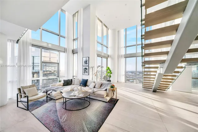 a living room with furniture and floor to ceiling windows