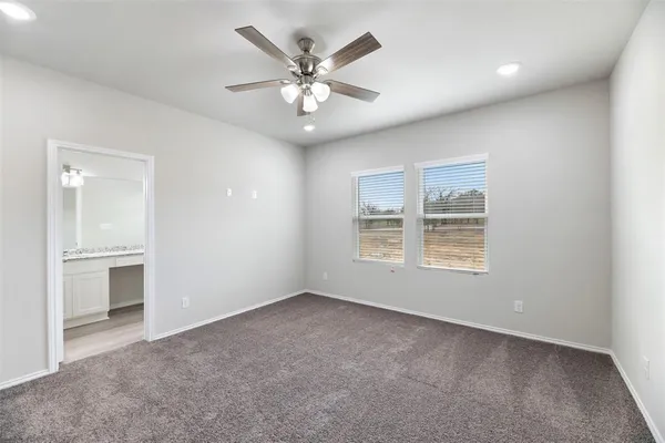 an empty room with windows and chandelier fan